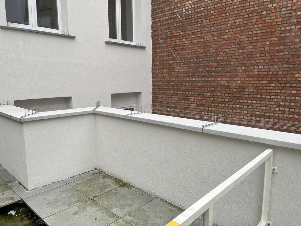 Supports et fils anti-pigeons sur les rebords en pierre d’une terrasse