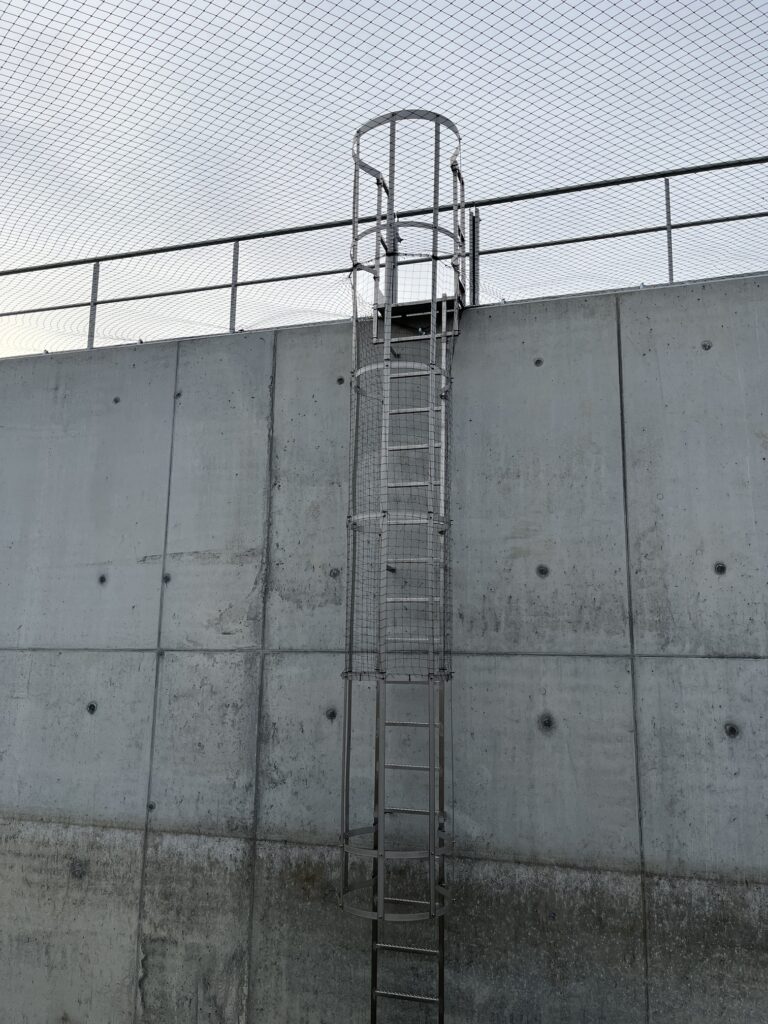 Filet au-dessus du bassin d’orage, avec mur en béton et échelle à crinoline