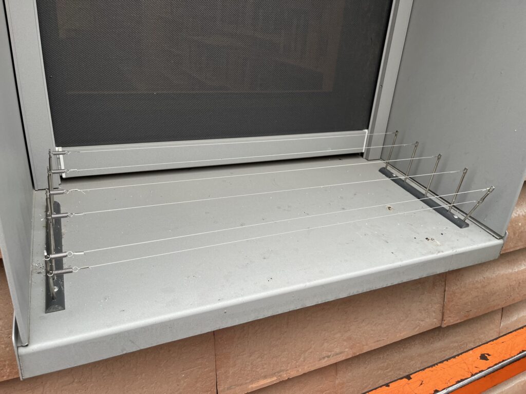 Rangées de fils tendus entre deux ensembles de supports sur un appui de fenêtre métallique