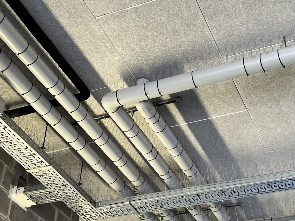 Conduites au plafond équipées de pics anti-pigeons à proximité des chemins de câbles