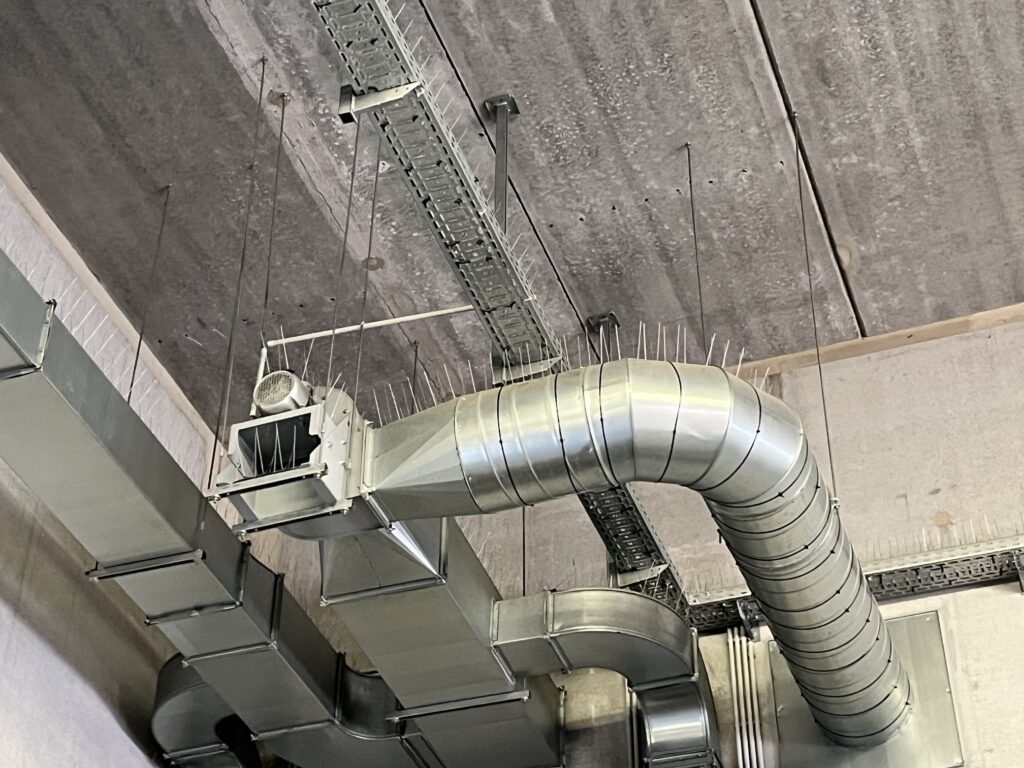 Pics anti-pigeons sur le dessus d’une gaine métallique courbe au plafond