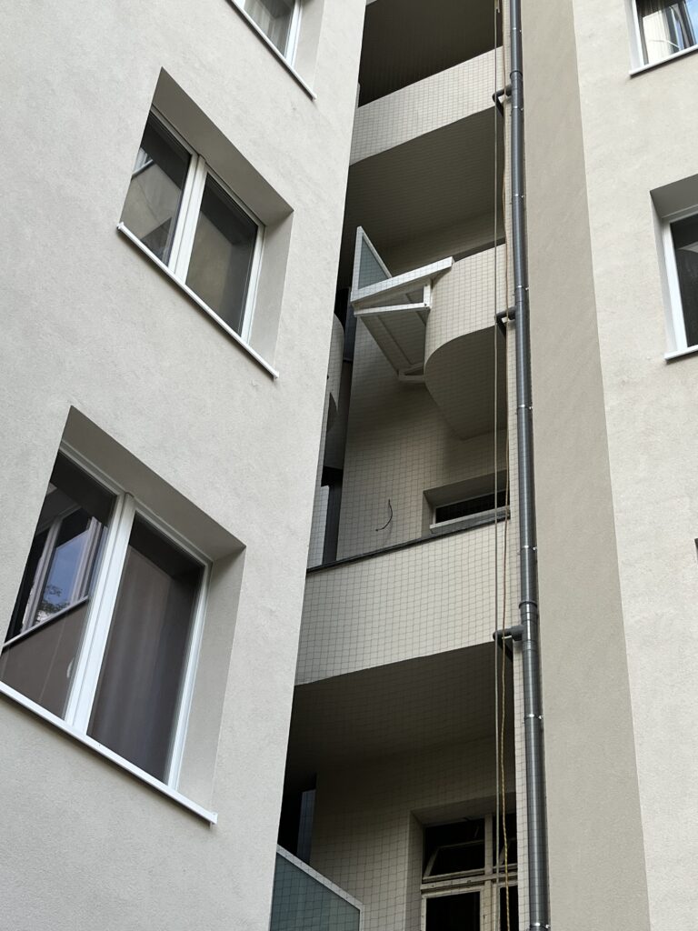 Filet anti-pigeons devant des balcons superposés entre deux façades